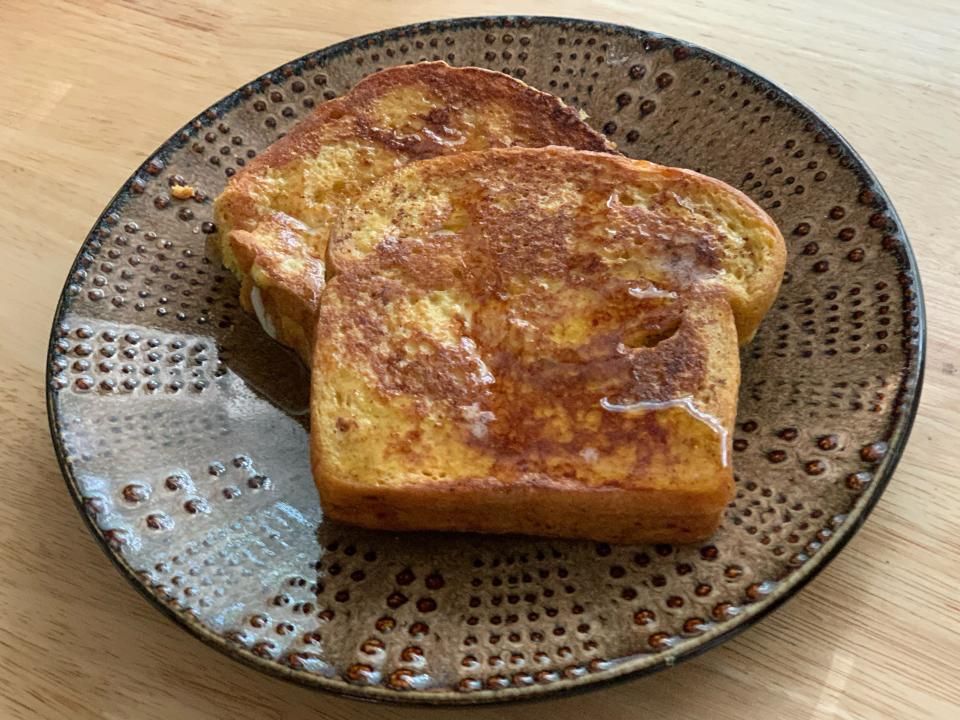 Trader Joe's pumpkin brioche as french toast on a plate with maple syrup on a brown plate