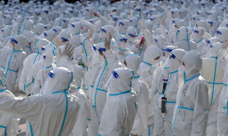 FILE PHOTO: Medical workers in protective suits wave at residents during a farewell ceremony, in Changchun