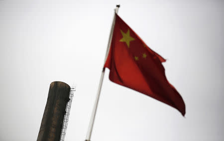 A Chinese national flag is seen in front of a chimney of a heat supply plant in Beijing May 13, 2014. REUTERS/Kim Kyung-Hoon/Files