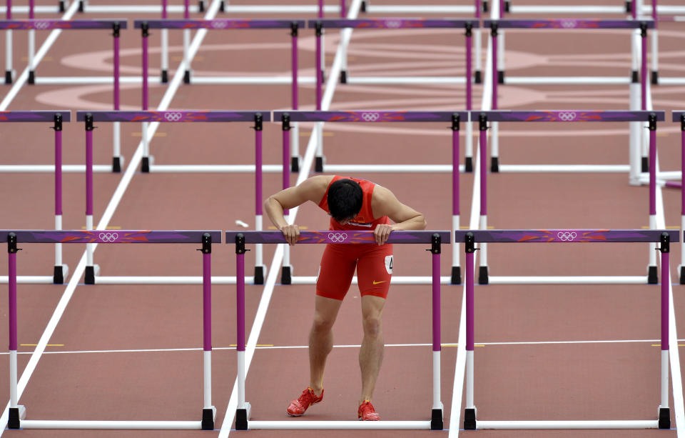 China's Liu Xiang kisses his hurdle after falling in a men's 110-meter hurdles heat during the athletics in the Olympic Stadium at the 2012 Summer Olympics, London, Tuesday, Aug. 7, 2012.(AP Photo/Martin Meissner)