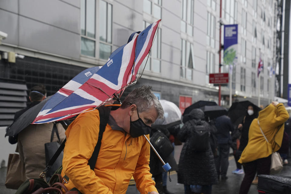 Delegates try to cope with the wet weather conditions as the wait to enter the Scottish Event Campus ahead of the COP26 Summit in Glasgow, Scotland, Sunday October 31, 2021. (Owen Humphreys/PA via AP)