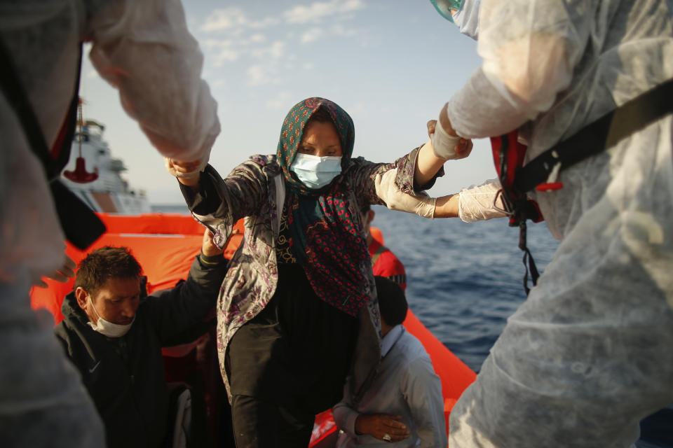 Turkish coast guard officers wearing protective gear to help prevent the spread of coronavirus, carry a woman off a life raft during a rescue operation in the Aegean Sea, between Turkey and Greece, Saturday, Sept. 12, 2020. Turkey is accusing Greece of large-scale pushbacks at sea — summary deportations without access to asylum procedures, in violation of international law. The Turkish coast guard says it rescued over 300 migrants "pushed back by Greek elements to Turkish waters" this month alone. Greece denies the allegations and accuses Ankara of weaponizing migrants. (AP Photo/Emrah Gurel)