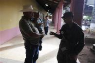 A man, holding his son, asks a soldier about the polling station at a school in Catacamas November 24, 2013. REUTERS/Tomas Bravo