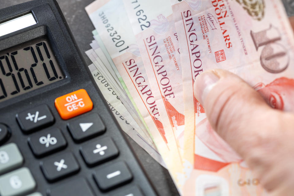 Image of a calculator on the left and Singapore dollar notes on the right, illustrating a story on filing income taxes.