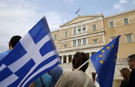 A pro-Euro protestor holds a Greek national flag and a European Union flag during a rally in front of the parliament building, in Athens, Greece, June 30, 2015. REUTERS/Yannis Behrakis