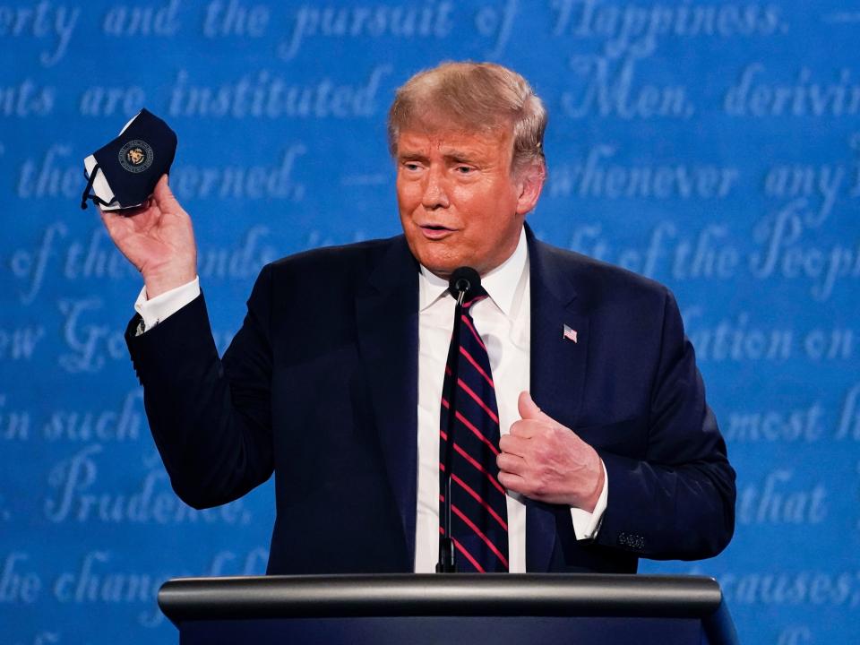 President Donald Trump holds up his face mask during the first presidential debate with Joe Biden in Cleveland, Ohio on September 29, 2020.