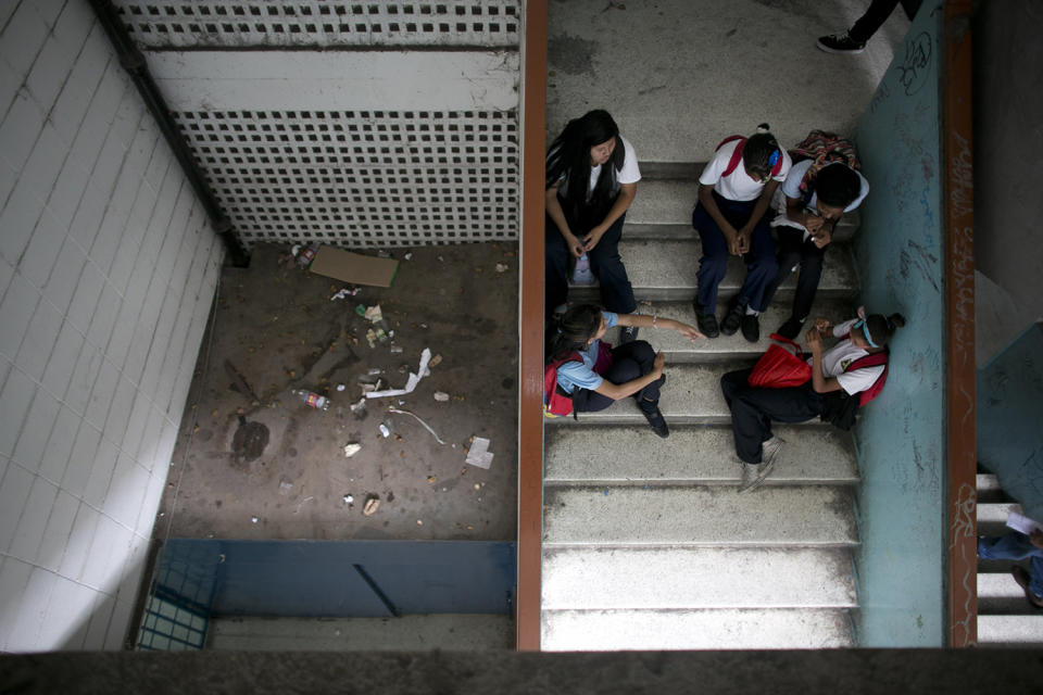 <p>Students sit on the stairs where trash fills one of the landings at their public high school in Caracas, Venezuela, June 1, 2016. The school looks less like a protected place of education than a downtown bus terminal; grimy, smelling of urine, and full of people waiting for teachers they’re only half-sure will come. (Ariana Cubillos/AP) </p>