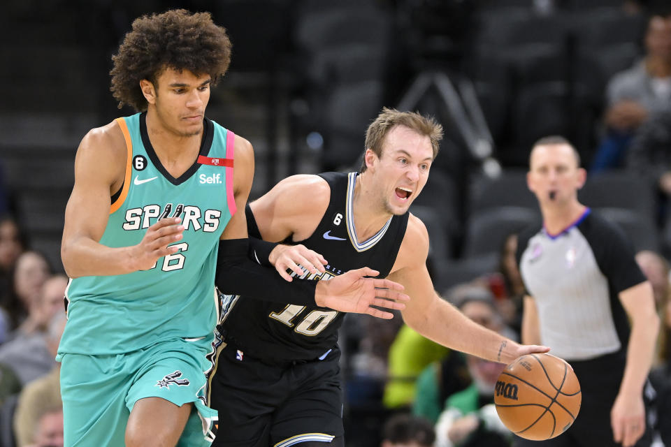 Memphis Grizzlies' Luke Kennard, right, drives around San Antonio Spurs' Dominick Barlow during the second half of an NBA basketball game, Friday, March 17, 2023, in San Antonio. (AP Photo/Darren Abate)