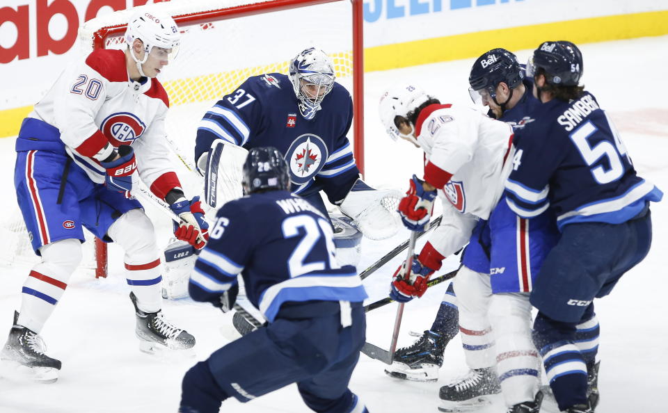 Winnipeg Jets goaltender Connor Hellebuyck (37) makes a save against a shot by Montreal Canadiens' Johnathan Kovacevic (26) during second-period NHL hockey game action in Winnipeg, Manitoba, Thursday, Nov. 3, 2022. (John Woods/The Canadian Press via AP)