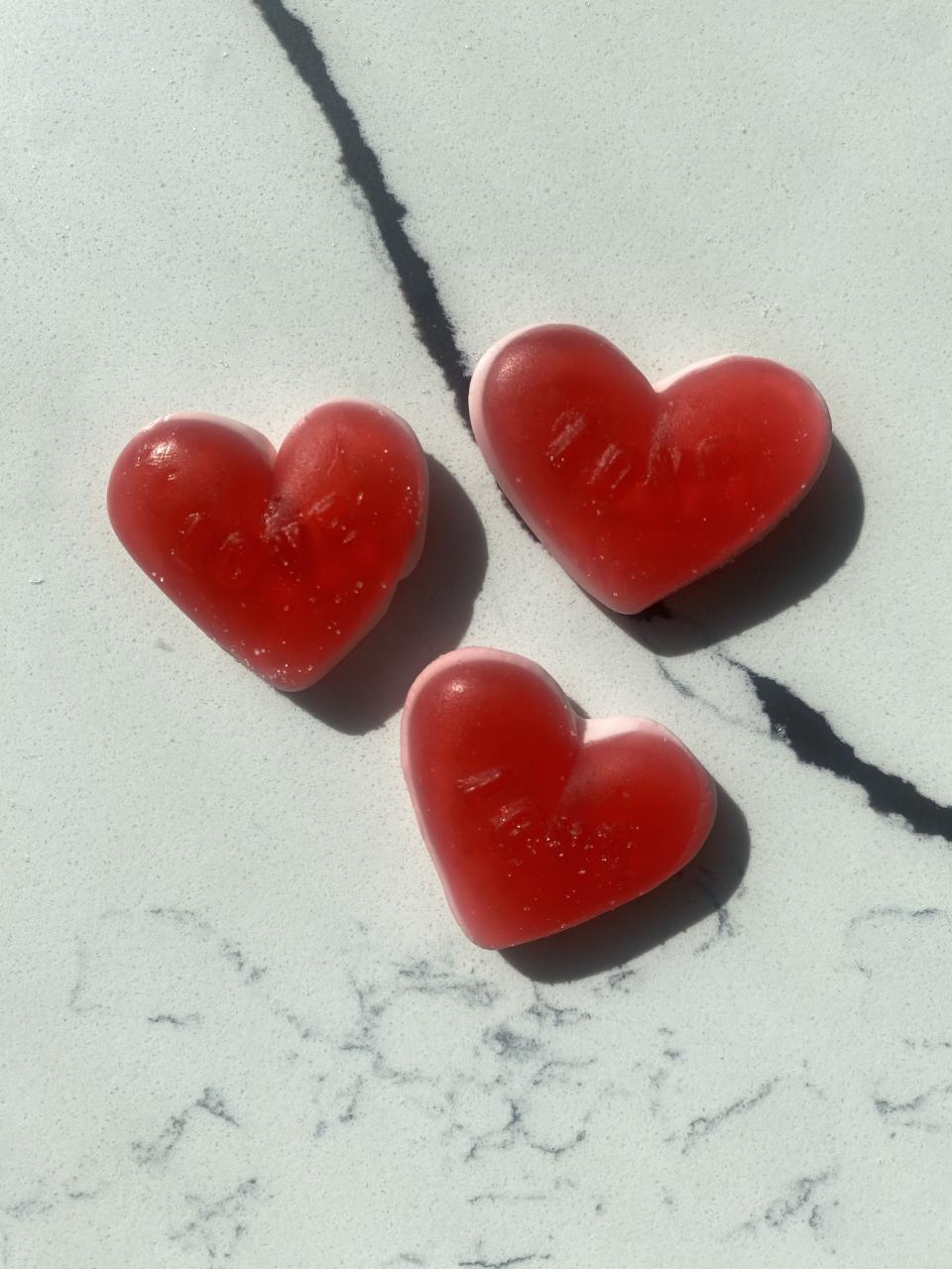 Three heart-shaped gummy candies on a marble surface