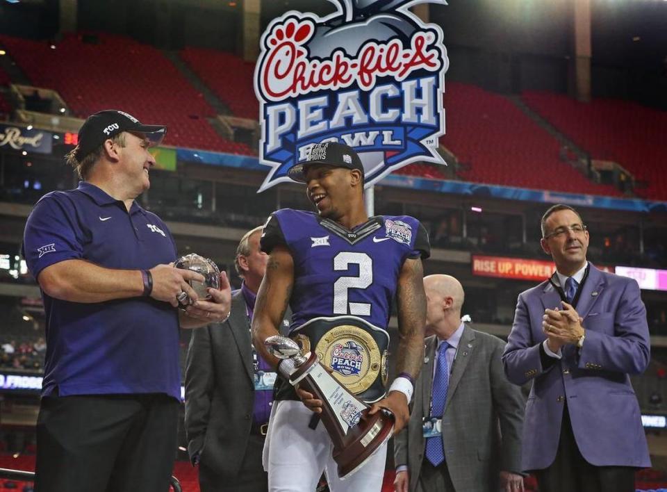 
TCU football coach Gary Patterson, left, and quarterback Trevone Boykin hold the game and offensive MVP trophies , respectively, from the Peach Bowl victory with  Chancellor Victor Boschini, second from right, and TCU athletic director Chris del Conte alson on stage.
