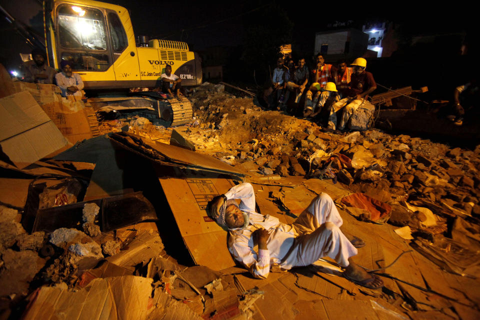 Rescue workers rest on the rubble of a factory that collapsed in Jalandhar, India, Wednesday, April 18, 2012. Rescue work continues at the site of a three-story blanket factory that collapsed in northern India close to midnight Sunday, killing at least five people. (AP Photo/Channi Anand)