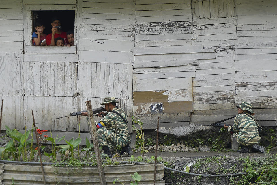 La gente mira desde una ventana mientras los soldados toman posición durante un simulacro de invasión en Caracas, Venezuela, el sábado 15 de febrero de 2020. (AP Foto / Matías Delacroix)