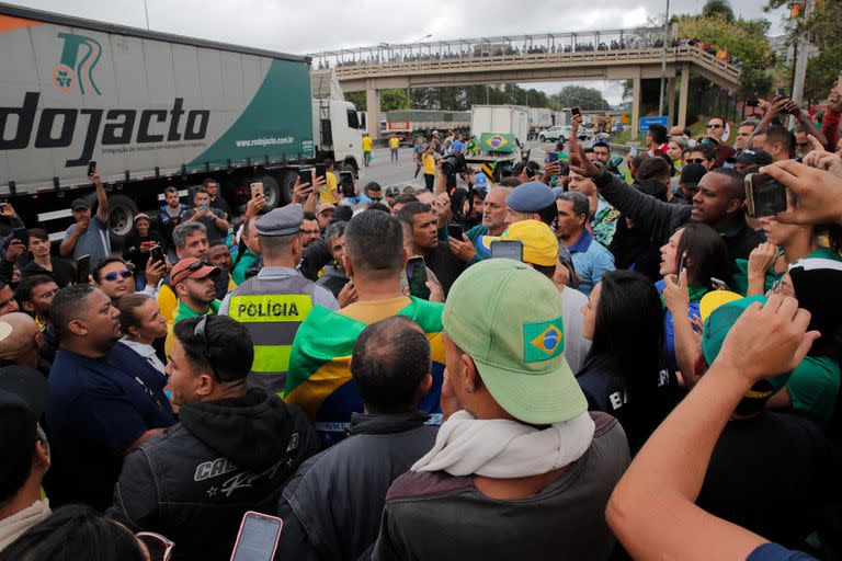 Supporters of President Jair Bolsonaro stand around police officers as they block Castelo Branco highway, on the outskirts of Sao Paulo, Brazil, on November 1, 2022. - Supporters of Brazilian President Jair Bolsonaro blocked major highways for a second day as tensions mounted over his silence after narrowly losing re-election to bitter rival Luiz Inacio Lula da Silva. Federal Highway Police (PRF) on Tuesday reported more than 250 total or partial road blockages in at least 23 states by Bolsonaro supporters, while local media said protests outside the country's main international airport in Sao Paulo delayed passengers and led to several flights being cancelled. (Photo by Caio GUATELLI / AFP)