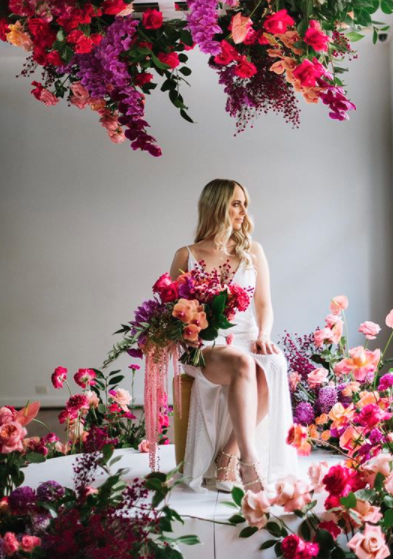 Bride in her wedding dress surrounded by purple flowers