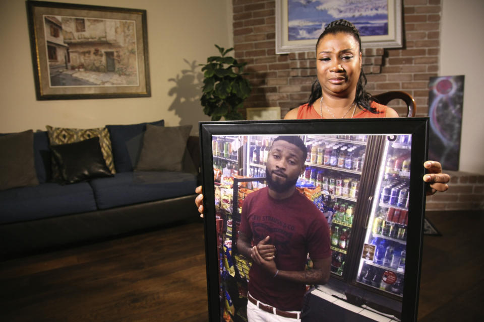 In this Monday, Aug. 19 2019, photo, Yvonne Ferguson-Smith, holds up a framed photo of her deceased son, Kenneth Roberson, at her Missouri City, Texas home. Ferguson-Smith, talked with The Associated Press about her son's 2018 death by a drive-by shooting, a crime which police believed they solved by a city wide bullet image database that tied the guns used in the murder to two known Houston gang members. (AP Photo/ John L. Mone)