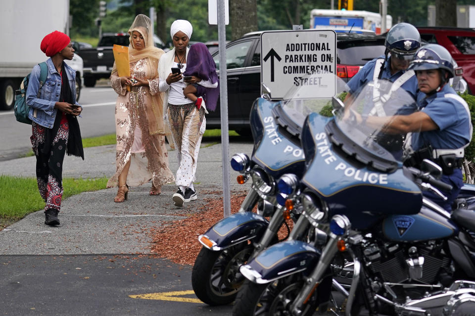 Three women walk past Massachusetts State Police troopers while arriving to sit in the gallery at Malden District Court, Tuesday, July 6, 2021, in Medford, Mass. The men arrested during an armed standoff on Interstate 95 in Massachusetts last weekend are scheduled to appear in court. (AP Photo/Charles Krupa)