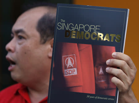 John Tan of the Singapore Democratic Party (SDP) holds a magazine outlining the party's history as part of a donation drive in Singapore August 8, 2010. REUTERS/Russell Boyce/Files