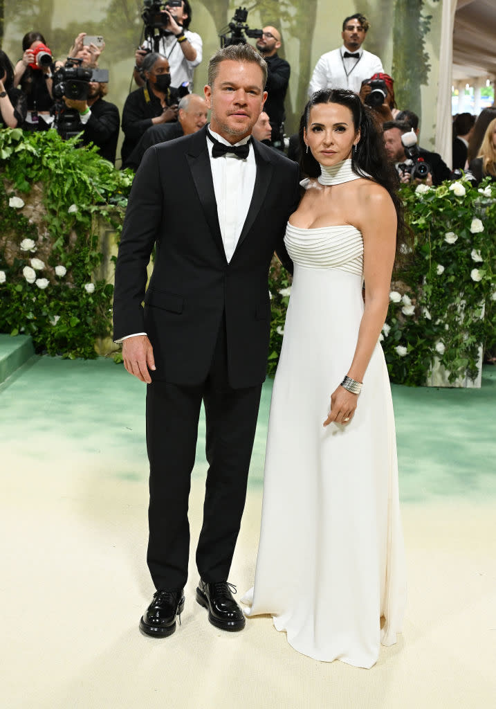 Man in a black tuxedo and woman in a strapless white gown posing together at an event