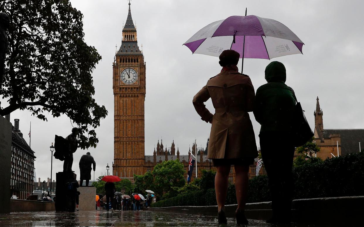 People shelter from the rain beneath an umbrella  - AFP or licensors