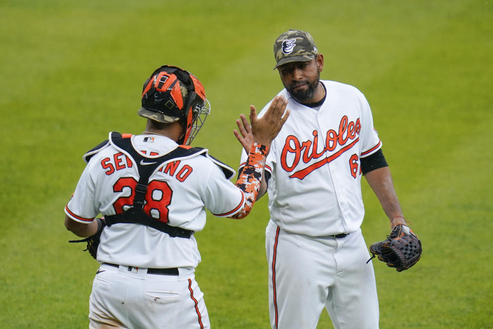 Baltimore Orioles catcher Pedro Severino (28) and relief pitcher Cesar Valdez celebrate after defeating the New York Yankees 10-6 during a baseball game, Sunday, May 16, 2021, in Baltimore. (AP Photo/Julio Cortez)