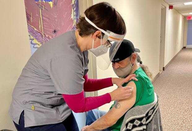 A health-care worker preps to give Joey Callaghan a dose of the Moderna vaccine, right outside his apartment door. (Nicole Williams/CBC - image credit)