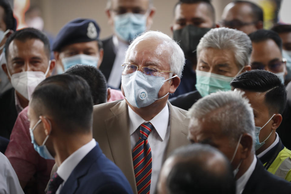 Former Malaysian Prime Minister Najib Razak, center, wearing a face mask with his supporters arrives at courthouse in Kuala Lumpur, Malaysia, Tuesday, July 28, 2020. Najib arrived for a verdict in the first of several corruption trials linked to the multibillion-dollar looting of the 1MDB state investment fund. (AP Photo/Vincent Thian)