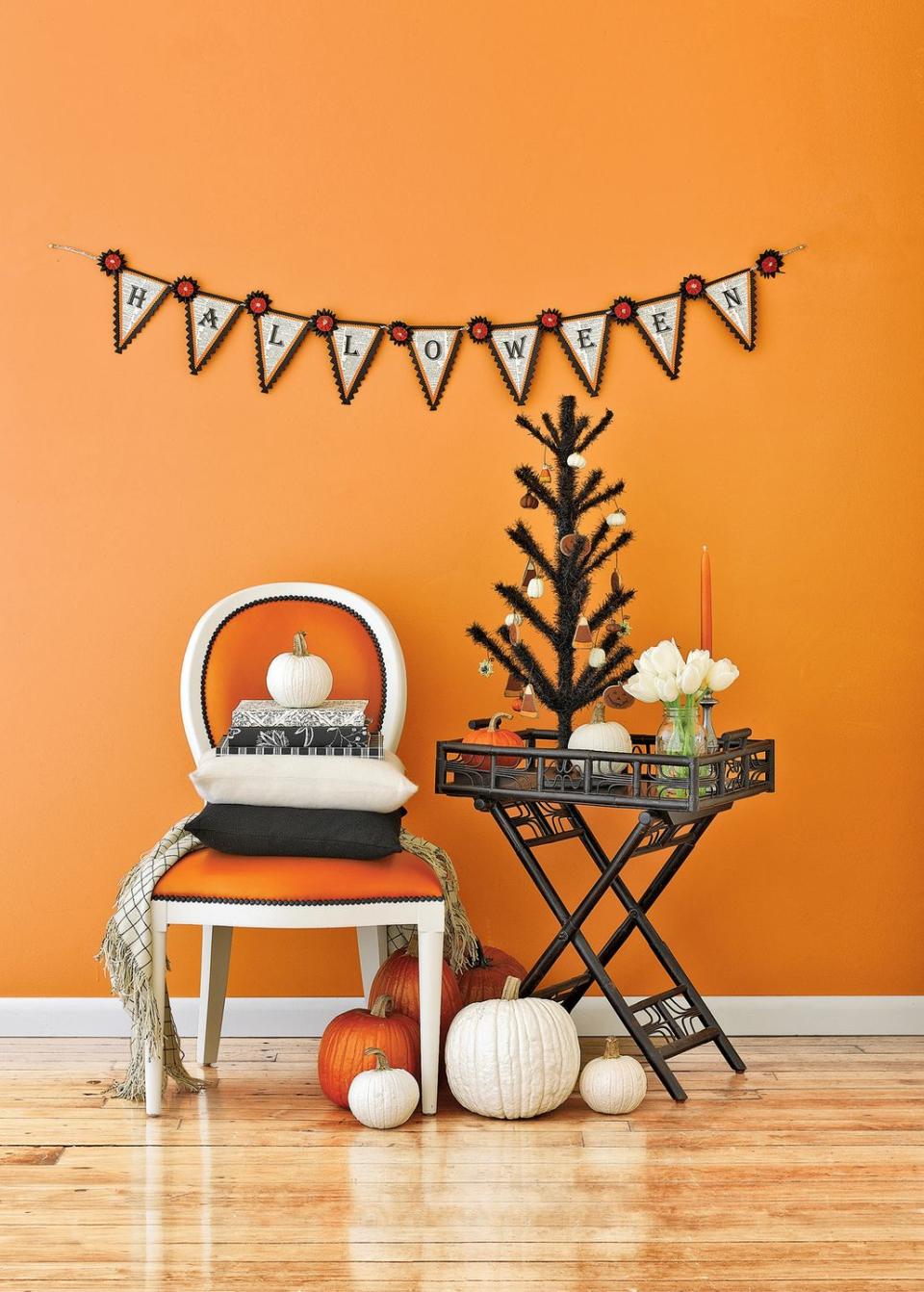 <p>Who says your bar cart can't have a part in your Halloween celebration? Jazz it up with an all-black tree, gourds, and an orange candlestick for a festive look.</p>