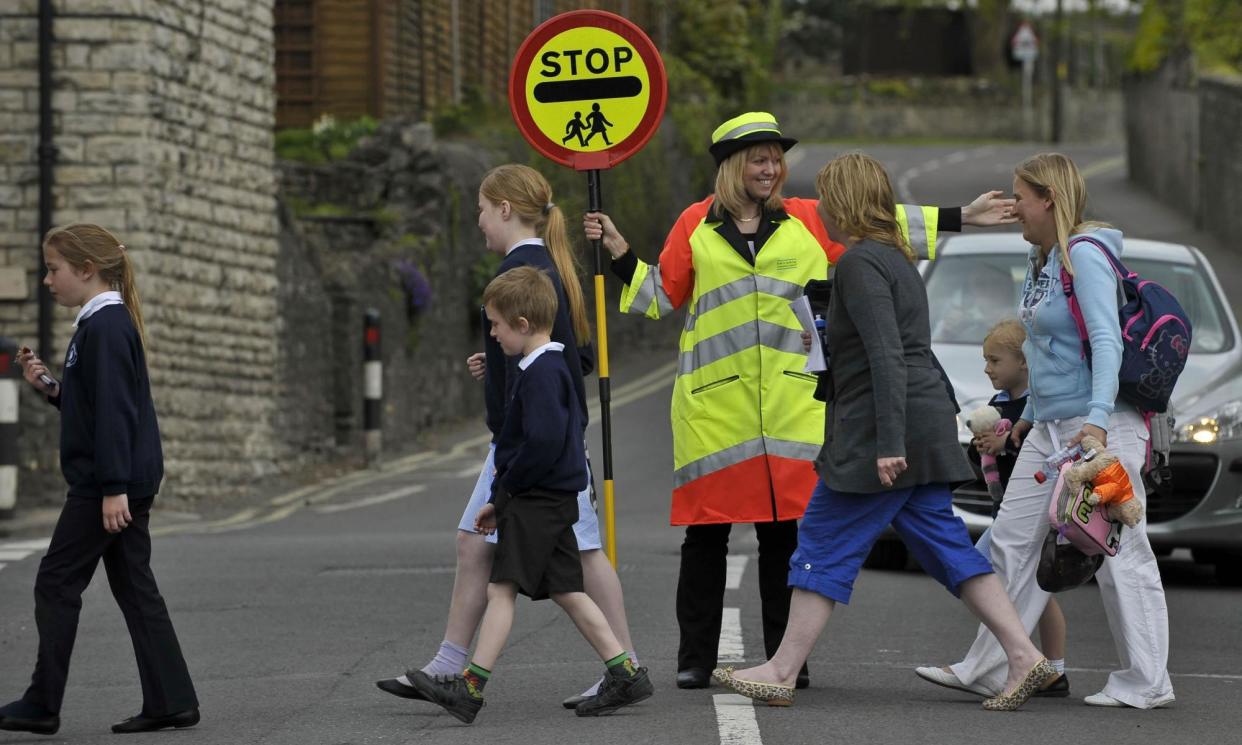 <span>A lollipop lady helping primary schoolchildren to cross the road.</span><span>Photograph: Ben Birchall/PA Archive/Press Association Images</span>