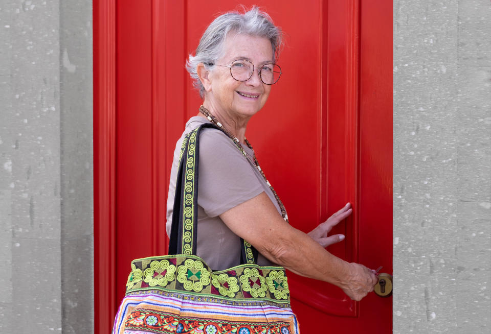 A smiling older woman about to open a door