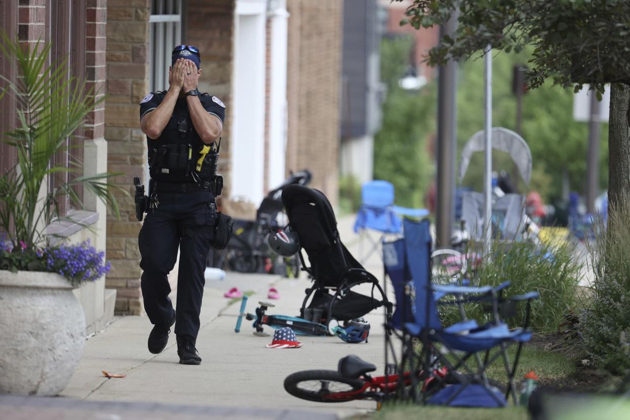 A police officer walks through the scene of the mass shooting in Highland Park, Ill.