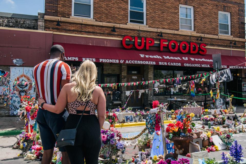 A couple pays their respects to George Floyd at the intersection of 38th Street and Chicago Avenue on Tuesday in Minneapolis. In cities around the U.S., groups honored the life of Floyd, who was murdered by Minneapolis Police officer Derek Chauvin on May 25, 2020.