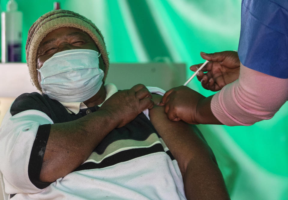 A retiree receives the first dose of the Pfizer coronavirus vaccine from a health worker inside a tent, during a mass vaccination program for the elderly at the clinic outside Johannesburg, South Africa, Monday, May 24, 2021. South Africa is in a race against time to vaccinate as many people as possible with signs the virus may be surging again. (AP Photo/Themba Hadebe)