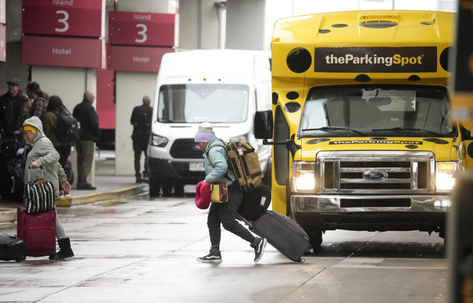 Traveller dodges shuttle buses on the way into Denver International Airport on Monday, Nov. 20, 2023, in Denver. Despite inflation and memories of past holiday travel meltdowns, millions of people are expected to hit airports and highways in record numbers over the Thanksgiving Day break. (AP Photo/David Zalubowski)