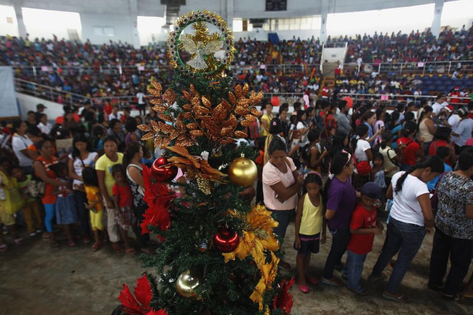 Survivors of onslaught of super Typhoon Haiyan queue in front of Christmas tree during gift giving activity inside astrodome at Tacloban