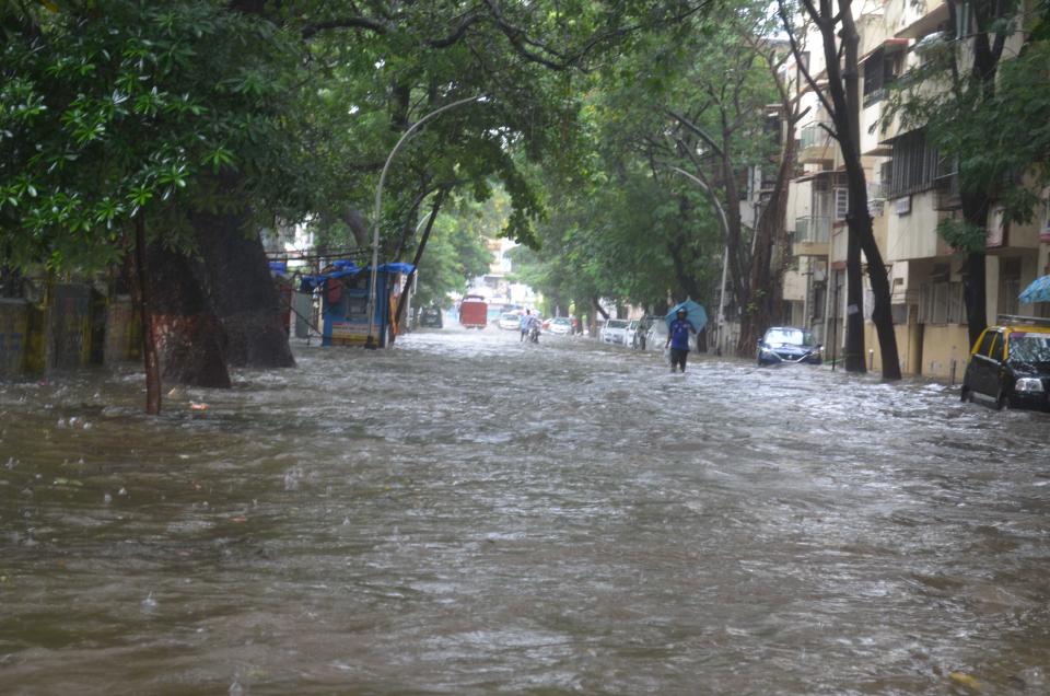 Commuters brave a flooded road in Mumbai. (Photo by Arun Patil)