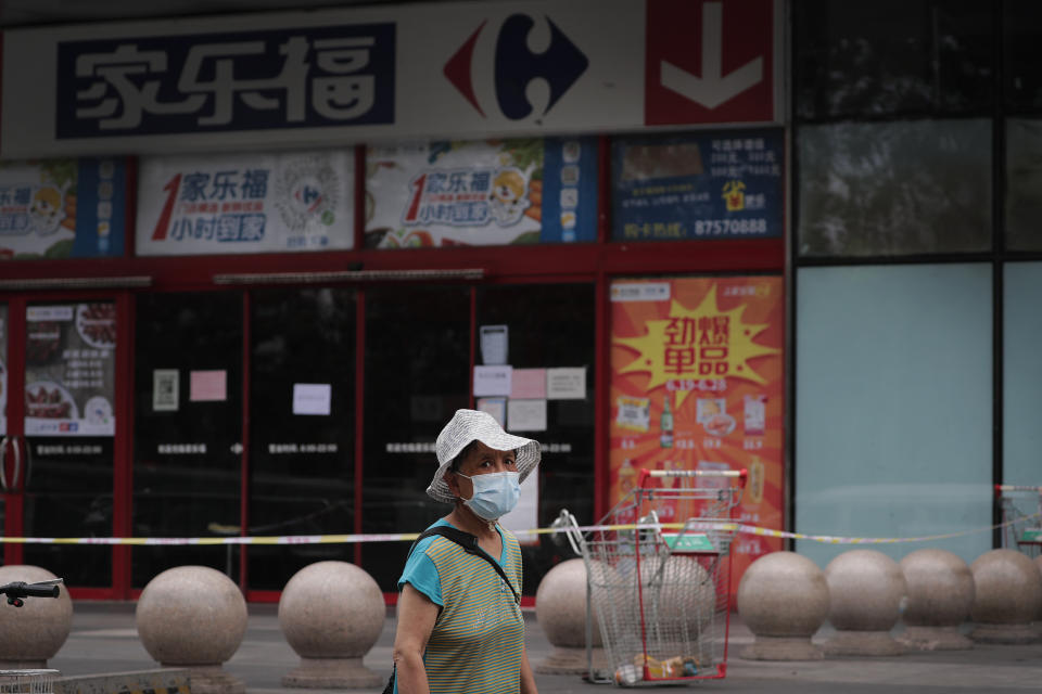 A woman wearing a protective face mask to help curb the spread of the new coronavirus walks by a barricaded Carrefour supermarket in a shuttered shopping mall following positive cases detected at the mall in Beijing, Tuesday, June 23, 2020. China reported close to two dozen new cases of coronavirus on Tuesday a day after a city government spokesperson said containment measures had slowed the momentum of an outbreak in the capital that has infected more than 200 people. (AP Photo/Andy Wong)