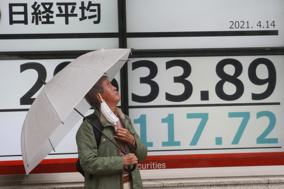 A man stands by an electronic stock board of a securities firm in Tokyo, Wednesday, April 14, 2021. Asian stock markets rose Wednesday after Wall Street hit a high following an uptick in U.S. inflation and an order by regulators to suspend use of Johnson & Johnson's coronavirus vaccine. (AP Photo/Koji Sasahara)