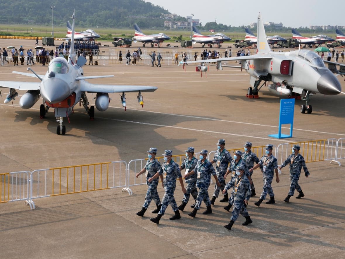 Chinese Air Force personnel march past the Chinese military's J10C fighter and JH-7A2 fighter bomber during 13th China International Aviation and Aerospace Exhibition, also known as Airshow China 2021, on Sept. 29, 2021 in Zhuhai. (Ng Han Guan/The Associated Press - image credit)