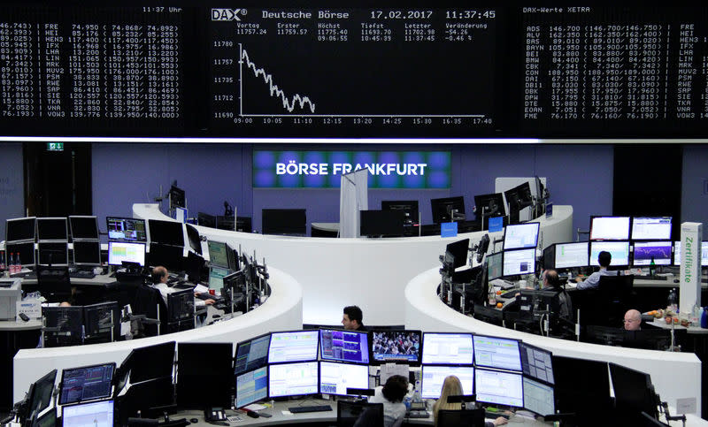 Traders work at their desks in front of the German share price index, DAX board, at the stock exchange in Frankfurt, Germany, February 17, 2017. REUTERS/staff/remote -