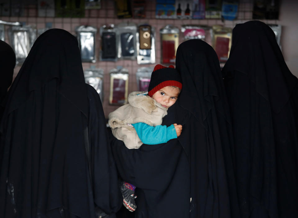 Tres mujeres, una de ellas con un niño en brazos, compran en una tienda del campamento de al-Hol. (Foto: Goran Tomasevic / Reuters).