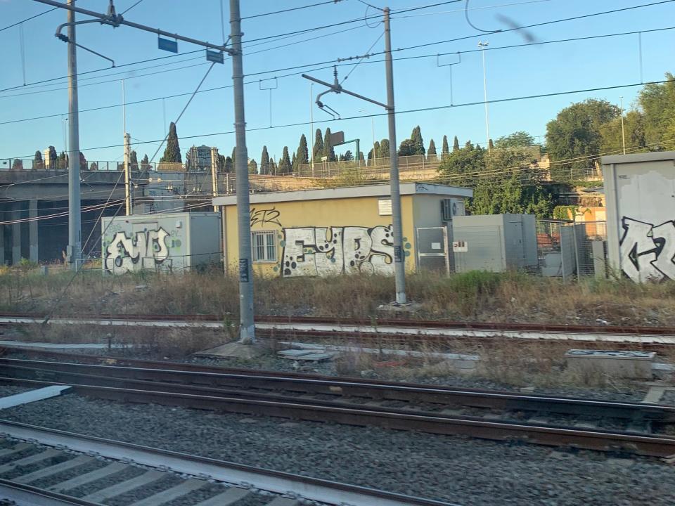 graffiti and train tracks outside a train window in a station in rome itlay