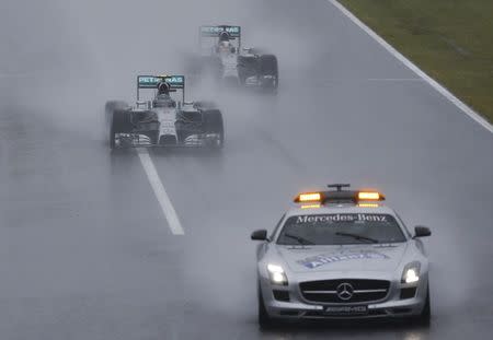 Mercedes Formula One driver Nico Rosberg of Germany leads team mate Lewis Hamilton of Britain behind a safety car as they start the first lap of the rain-affected Japanese F1 Grand Prix at the Suzuka Circuit October 5, 2014. REUTERS/Toru Hanai