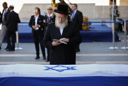 Israeli member of parliament Yisrael Eichler prays besides the flag-draped coffin of former Israeli President Shimon Peres, as he lies in state at the Knesset plaza, the Israeli parliament, in Jerusalem September 29, 2016. REUTERS/Ronen Zvulun