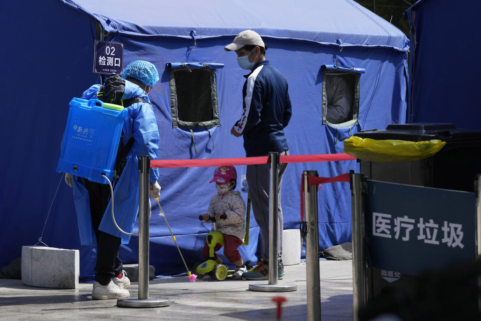 A worker in protective overall disinfects the area as residents line up for mass COVID test on Wednesday, May 11, 2022, in Beijing. (AP Photo/Ng Han Guan)