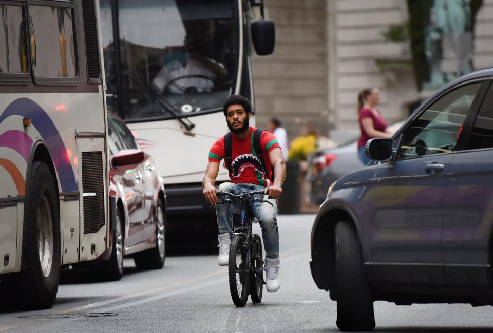 A young man rides a bike in busy traffic in downtown Paterson, N.J.