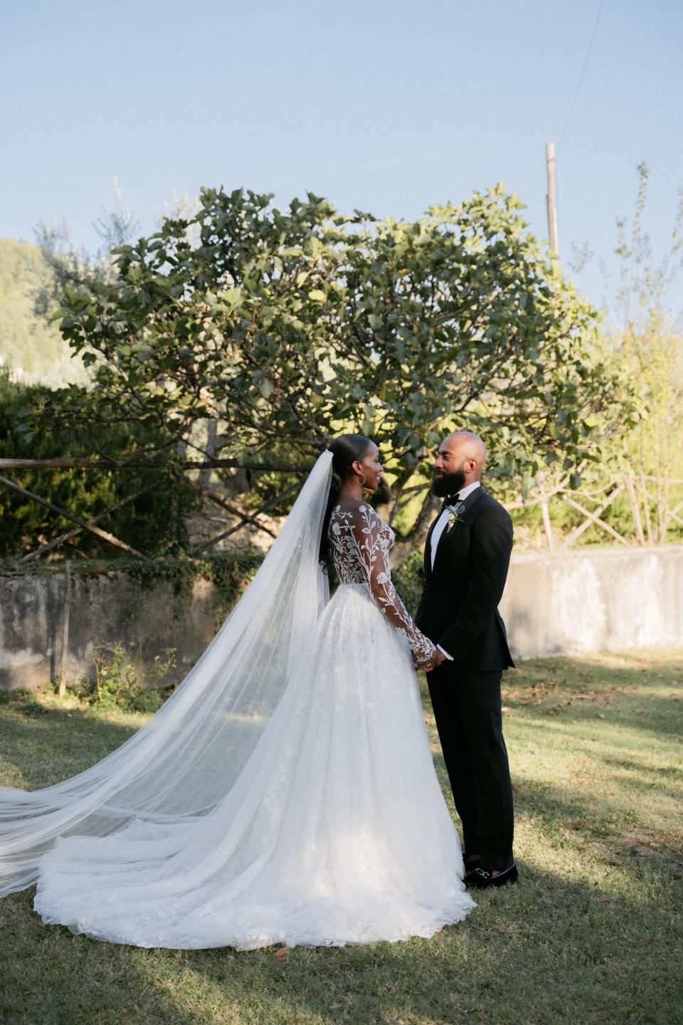 A bride and groom look at each other in a field.