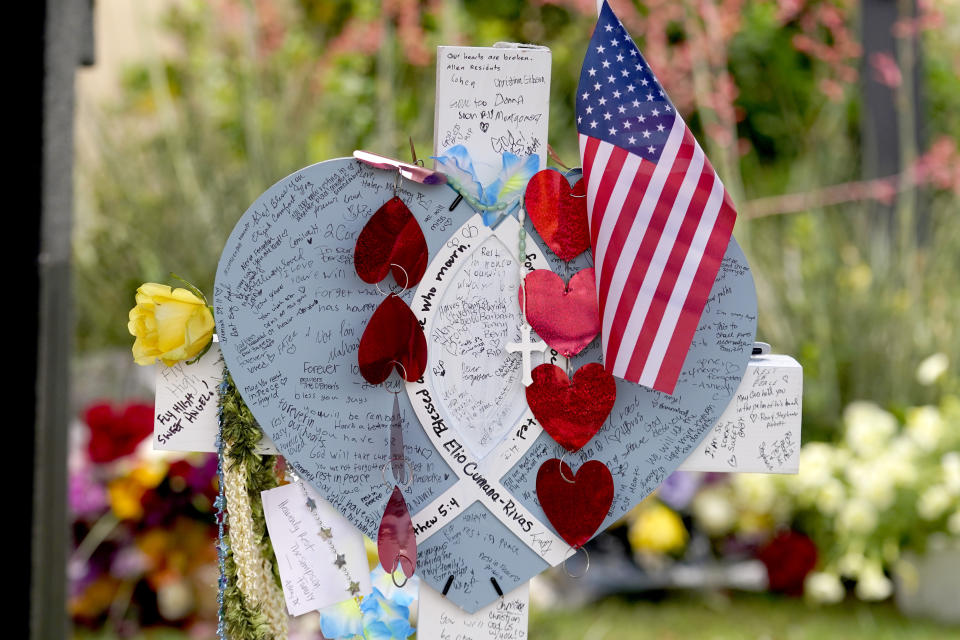 A cross with the name, Elio Cumana-Rivas, a victim of Saturday's mass shooting, stands at a makeshift memorial by the mall where several people were killed, Wednesday, May 10, 2023, in Allen, Texas. Cumana-Rivas, 32, had moved to Texas from Brazil. (AP Photo/Tony Gutierrez)