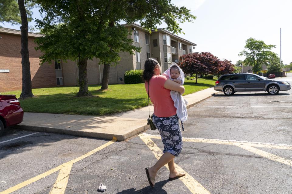 Yury Navas, 29, of Laurel, Md., walks through her apartment complex to the grocery store where she hopes to find more formula, while holding her two-month-old baby Ismael Galvaz, in Laurel, Md., Monday, May 23, 2022. After this day's feedings she will be down to their last 12.5 ounce container of formula. Navas doesn't know why her breastmilk didn't come in for her third baby and has tried many brands of formula before finding the one kind that he could tolerate well, which she now says is practically impossible for her to find. To stretch her last can she will sometimes give the baby the water from cooking rice to sate his hunger. The store by her home yet again had none of the only type of formula that her baby can take without digestive upset. (AP Photo/Jacquelyn Martin)