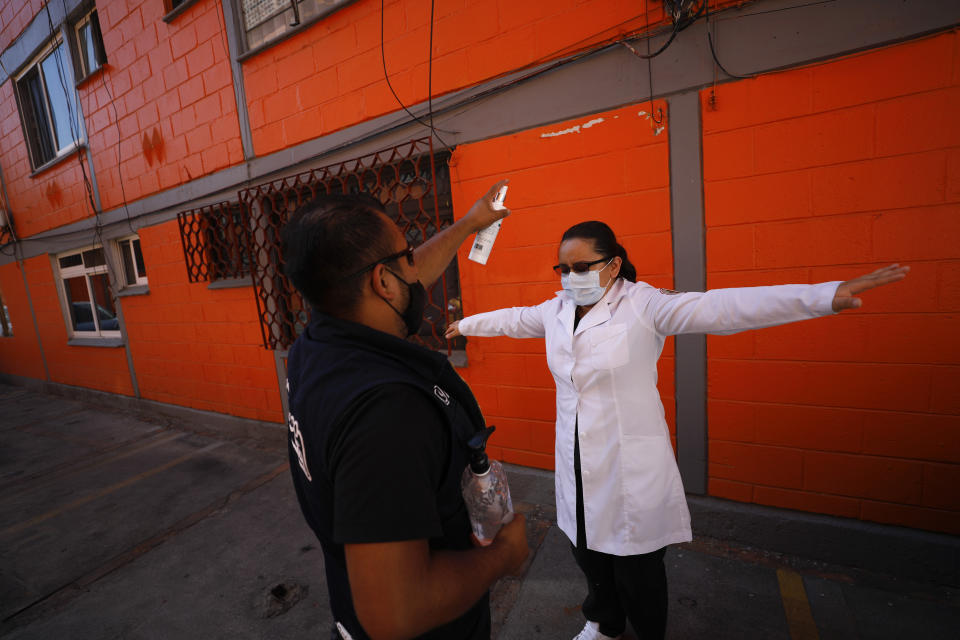 Dr. Monserrat Castaneda is sprayed with a disinfectant after conducting a COVID-19 test inside a home, in the Venustiano Carranza borough of Mexico City, Thursday, Nov. 19, 2020. (AP Photo/Rebecca Blackwell)